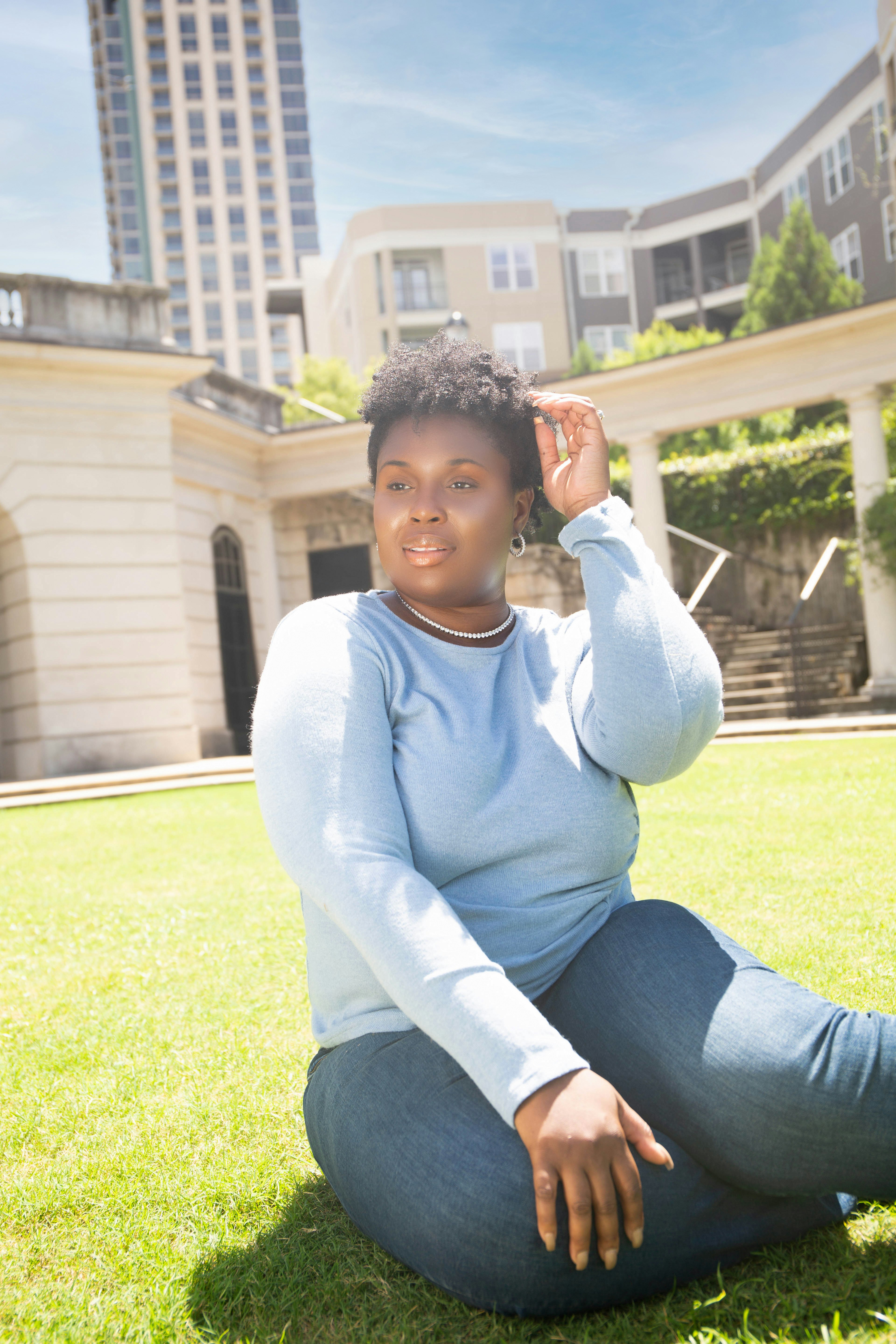 woman in white long sleeve shirt sitting on green grass field during daytime